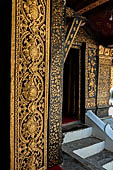 Wat Xieng Thong temple in Luang Prabang, Laos. The facade of the sim decorated with gold stencilling on a black lacquer background. 